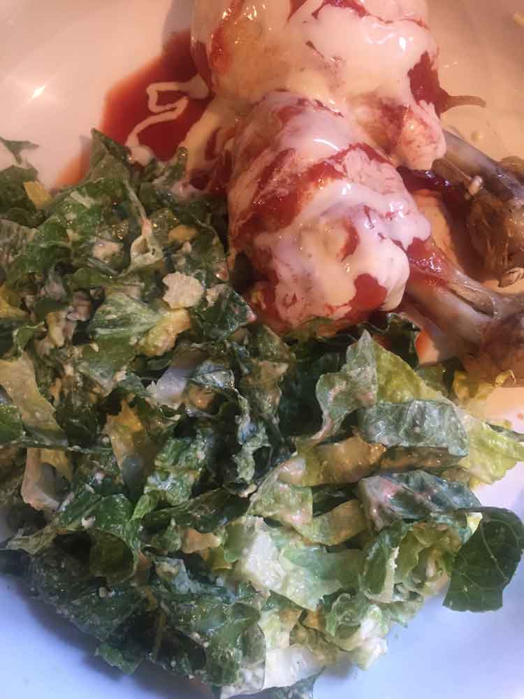 Spicy chicken legs with blue cheese dressing and caesar salad.