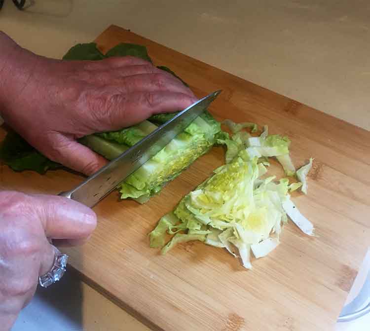 photo of a hand chopping lettuce on a chopping board