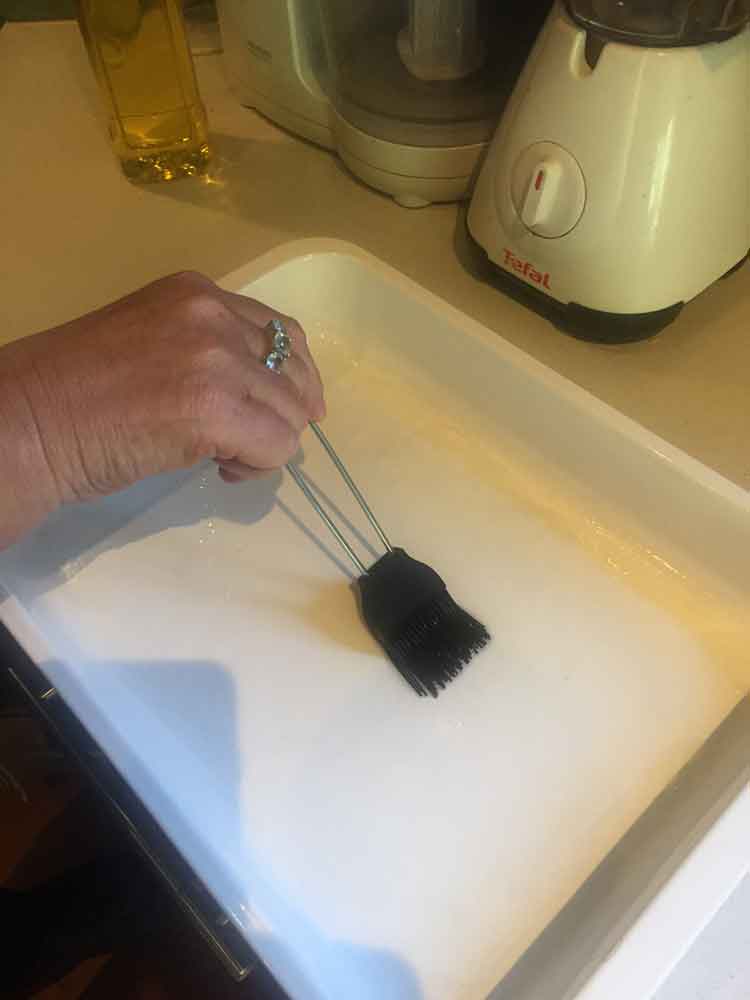 photo of a hand painting oil onto a roasting dish