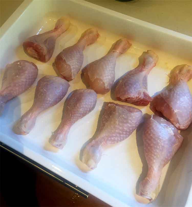 photo of raw chicken legs in a roasting pan