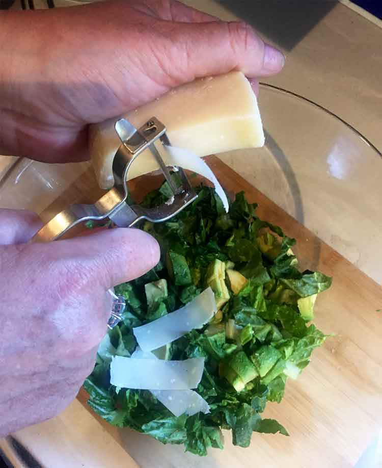 photo of hand using potato peeler to slice cheese