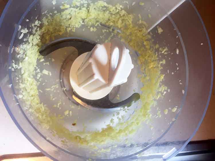 photo of garlic and ginger in a food processor in small bits: Keto cauliflower- egg-fried rice.